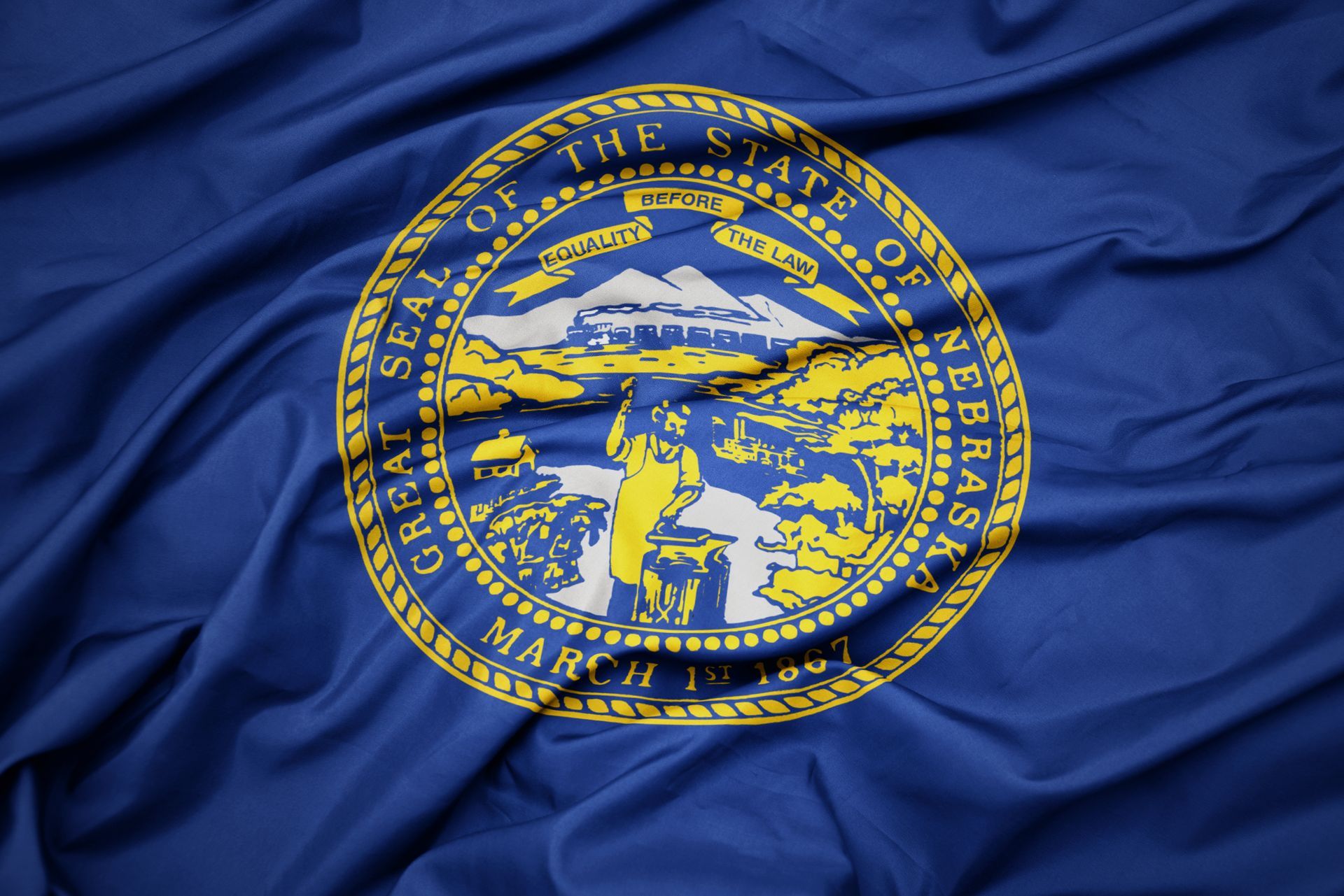 Blue Nebraska state flag with the state seal waving on fabric.