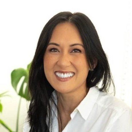 Portrait of a smiling woman in a white shirt against a bright indoor background