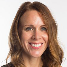 Smiling woman with wavy brown hair against a light background