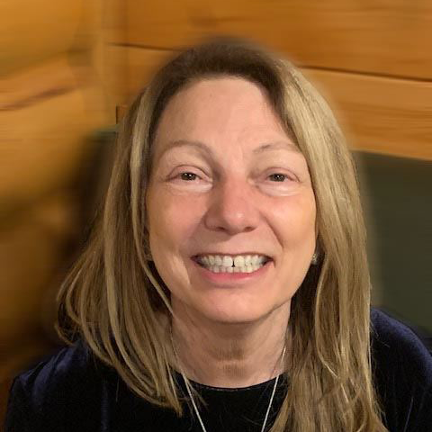 Smiling person with glasses in a bright indoor setting