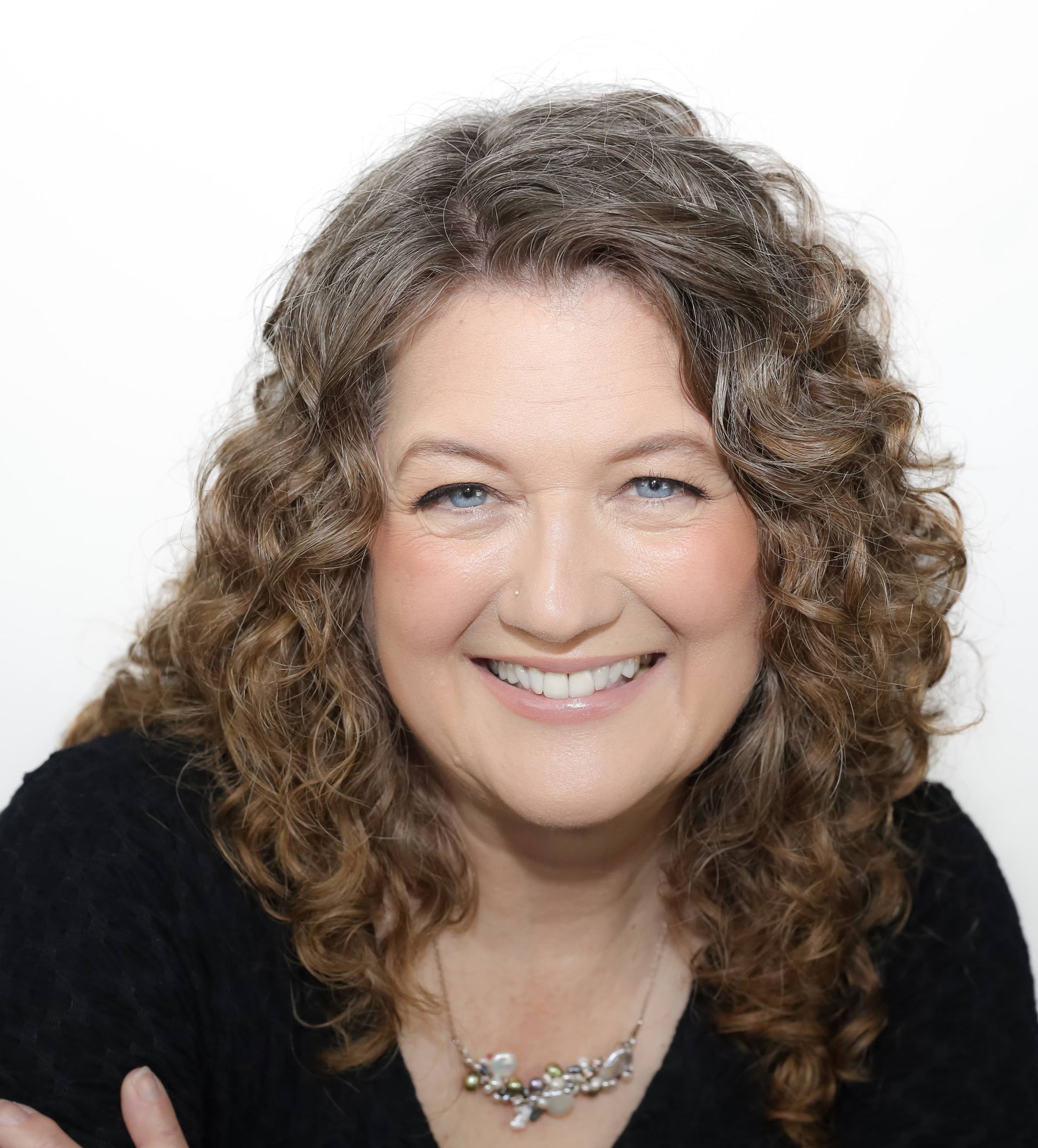 Portrait of a smiling person with glasses and dark hair against a light background