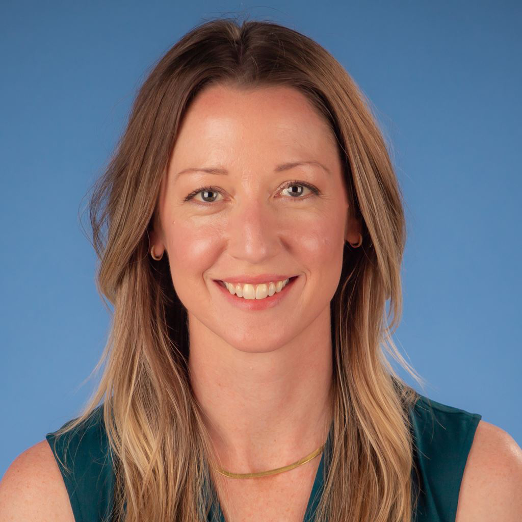 Smiling woman with long light brown hair against a blue background
