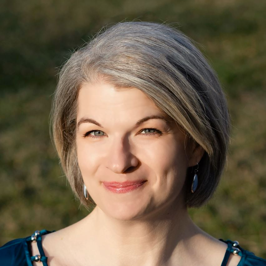 Smiling woman with short gray hair outdoors in soft sunlight