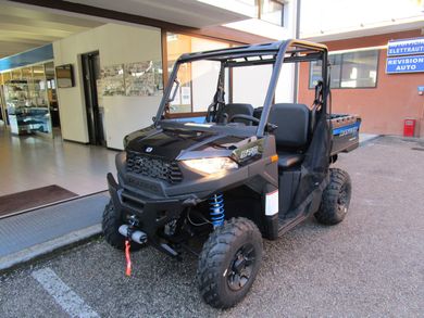 Veicolo fuoristrada nero parcheggiato al chiuso con i fari accesi e un gancio di traino rosso.
