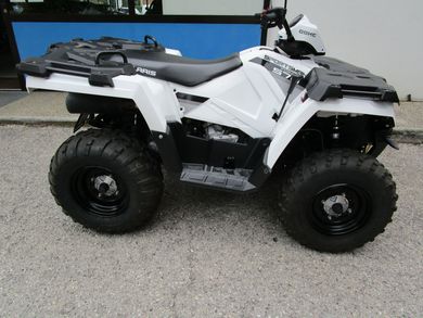 Quad bianco con ruote nere parcheggiato sul marciapiede di fronte a un muro blu.