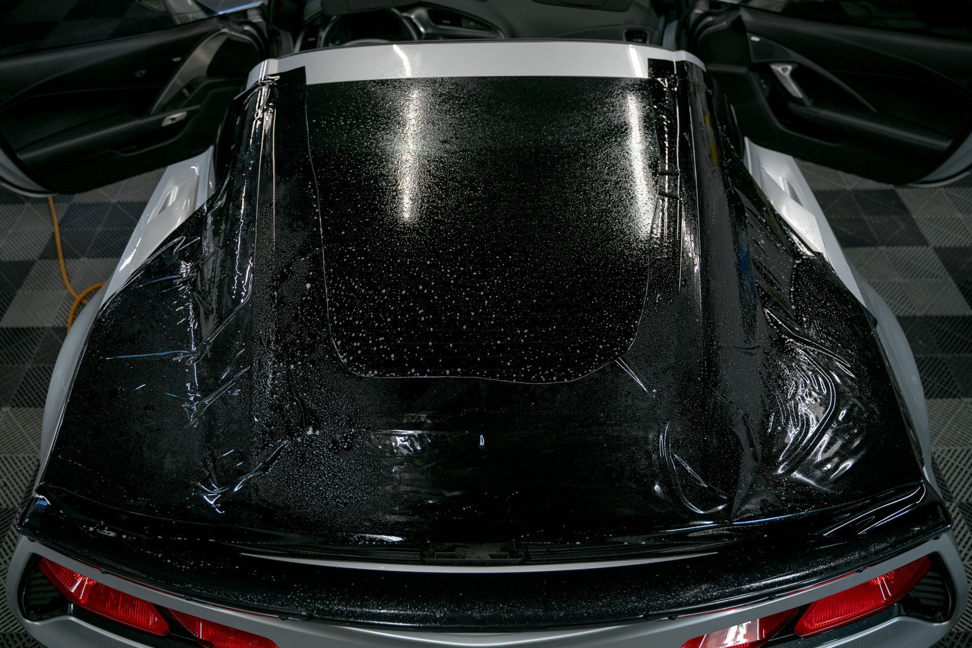 Top view of a black sports car covered in water droplets under low light