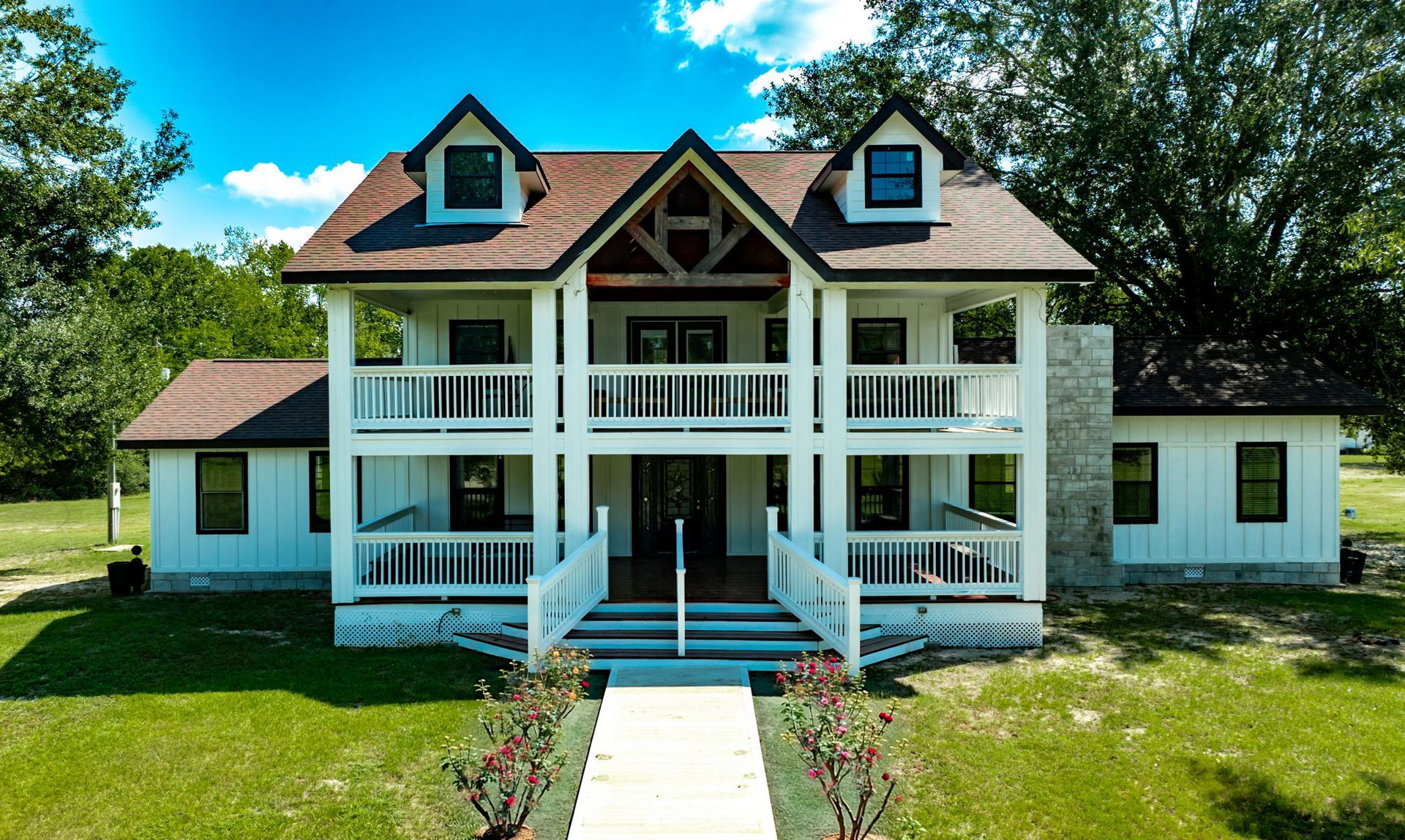 Front of The Greystone Estate farmhouse with double porches and a rose-lined walkway
