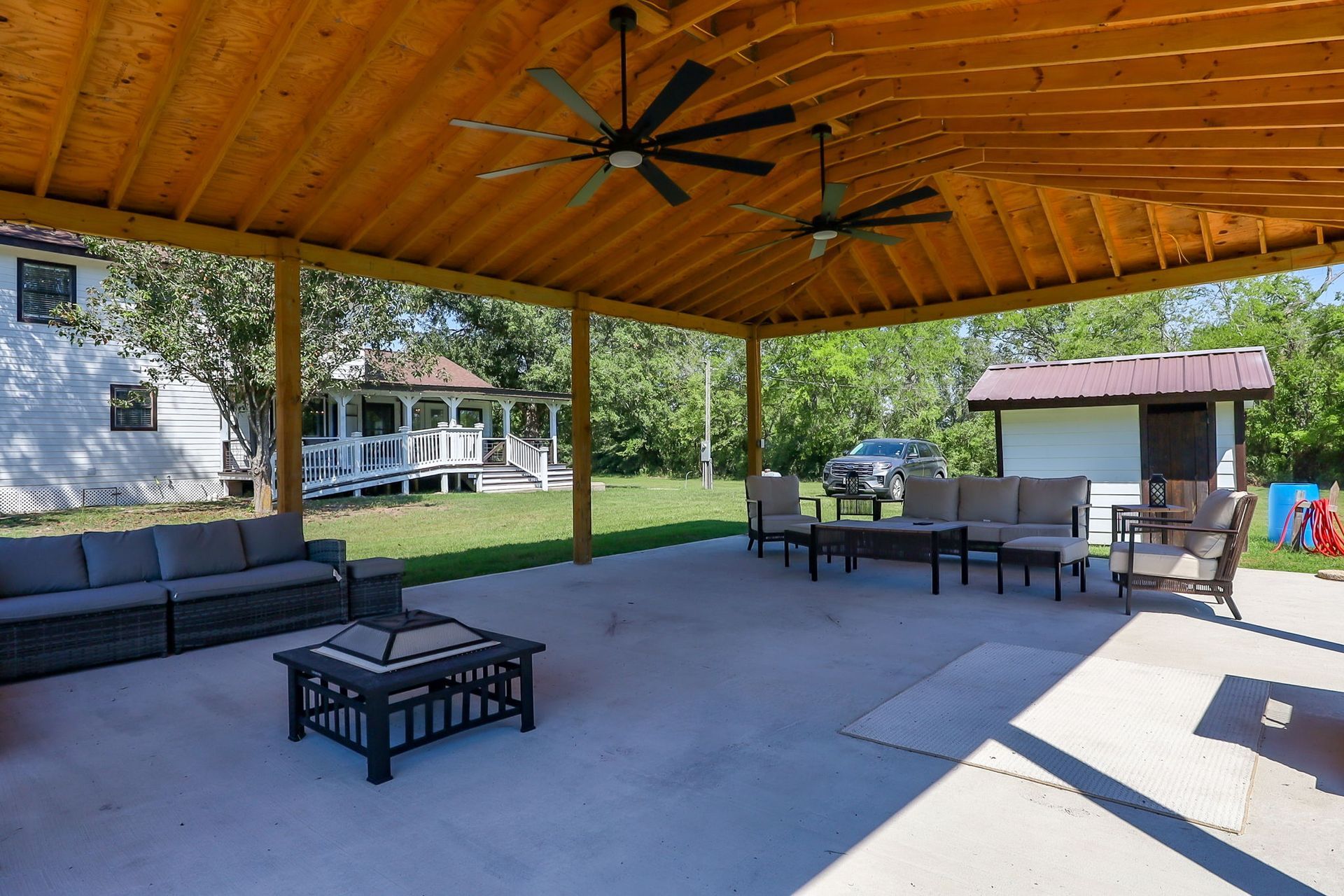 Covered outdoor pavilion with lounge seating, fire pit, and ceiling fans