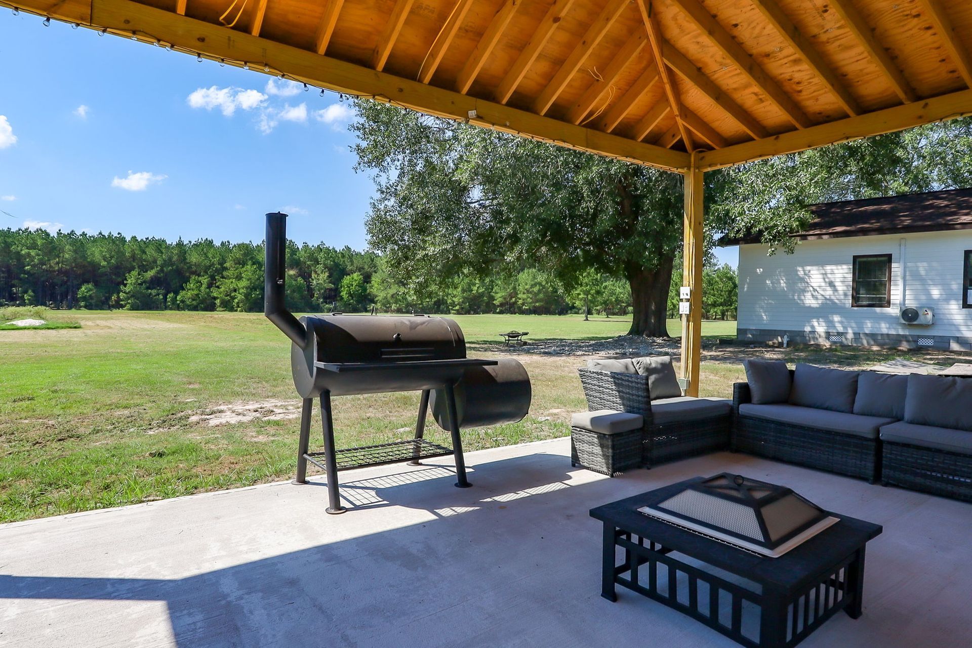 Covered pavilion with smoker grill and lounge seating overlooking the lawn