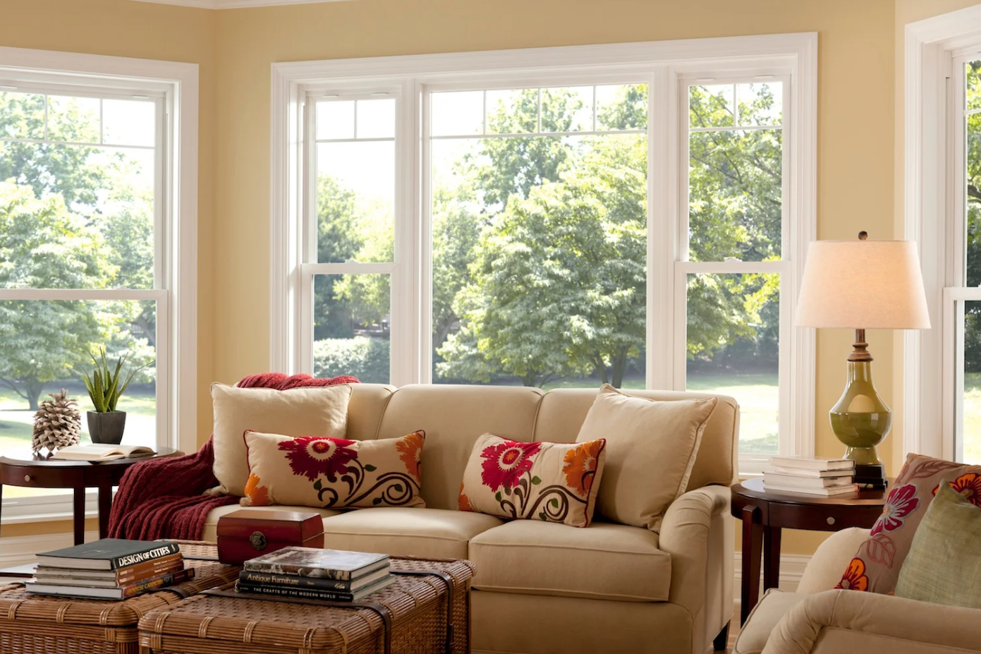 A living room with a couch , chair , table , lamp and lots of windows.