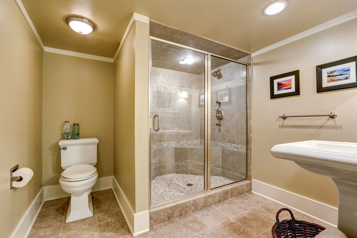 A bathroom with a toilet , sink and walk in shower.