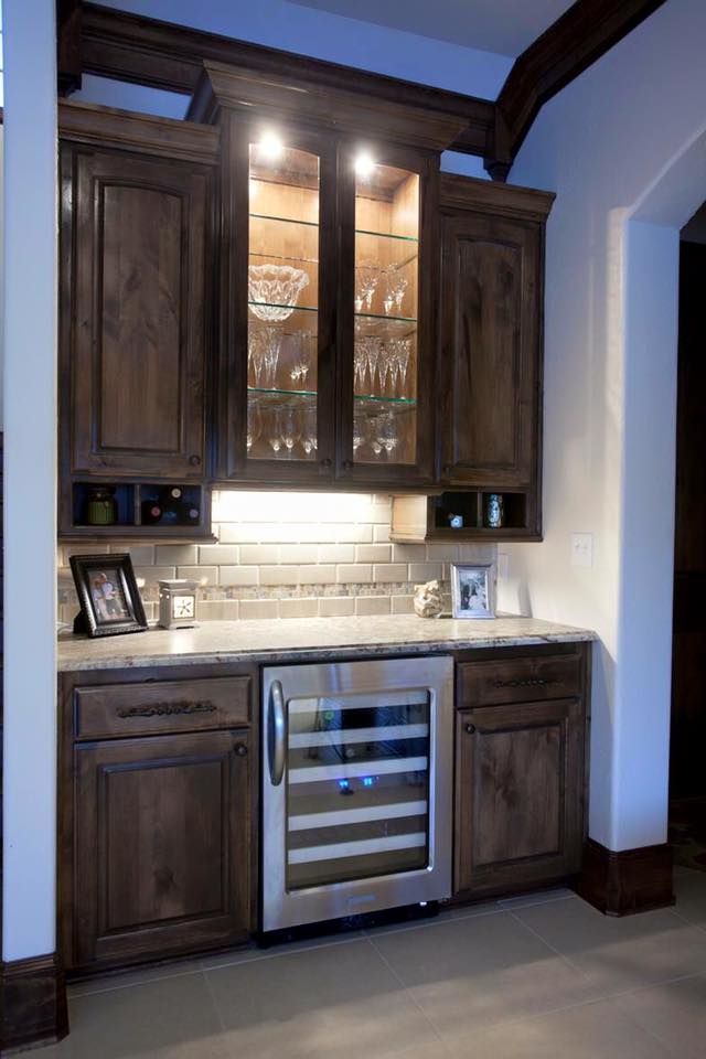 A kitchen with wooden cabinets and a stainless steel wine cooler