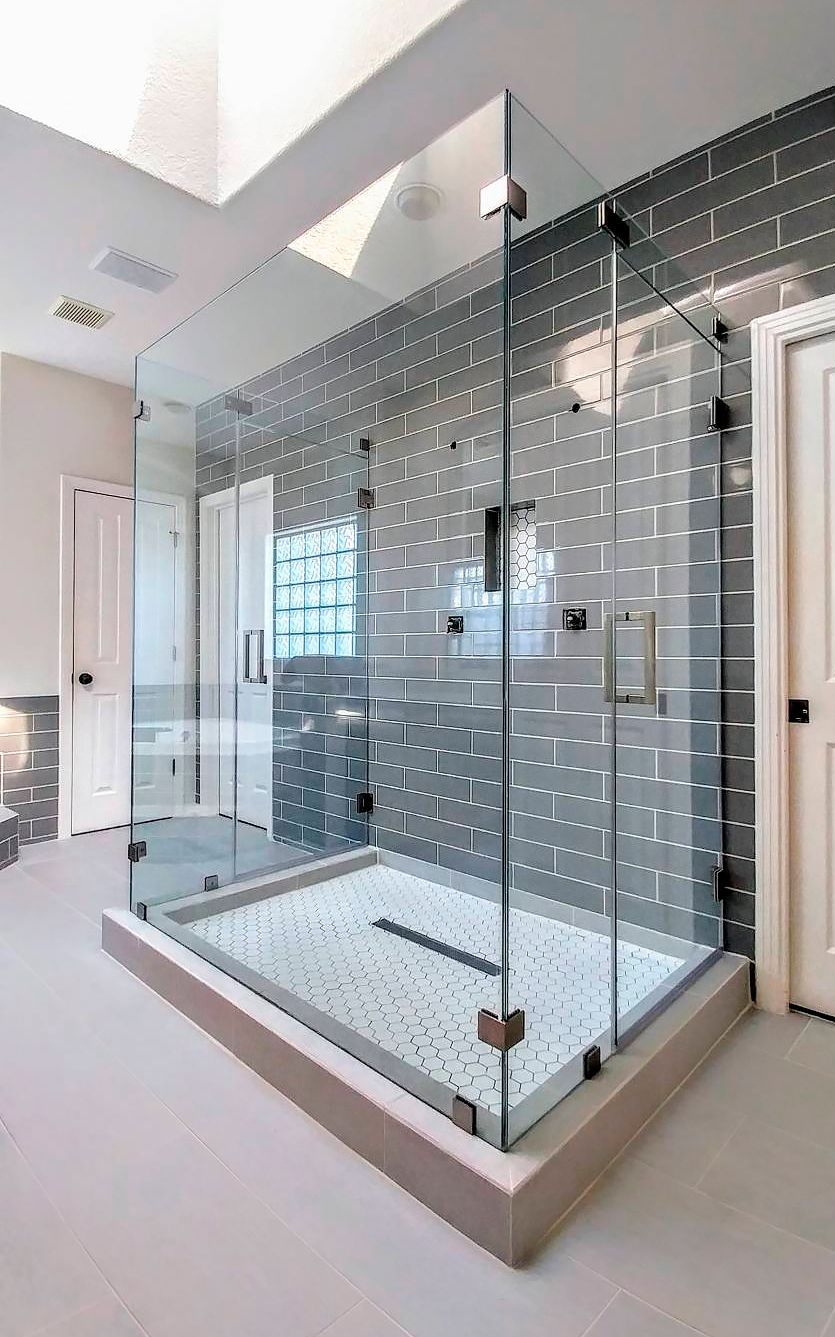 A bathroom with a walk in shower with a glass door.