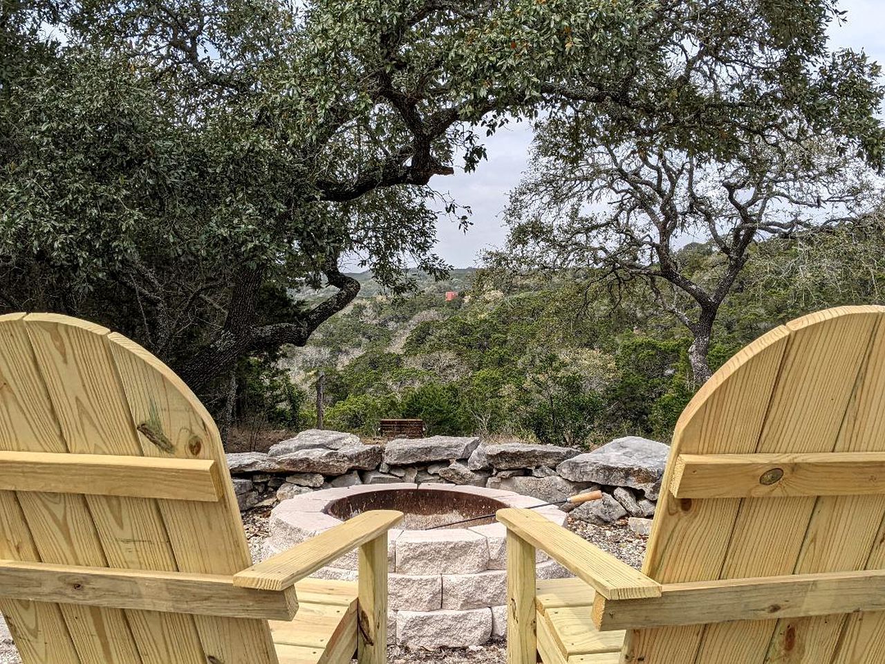 Two wooden chairs are sitting in front of a fire pit.