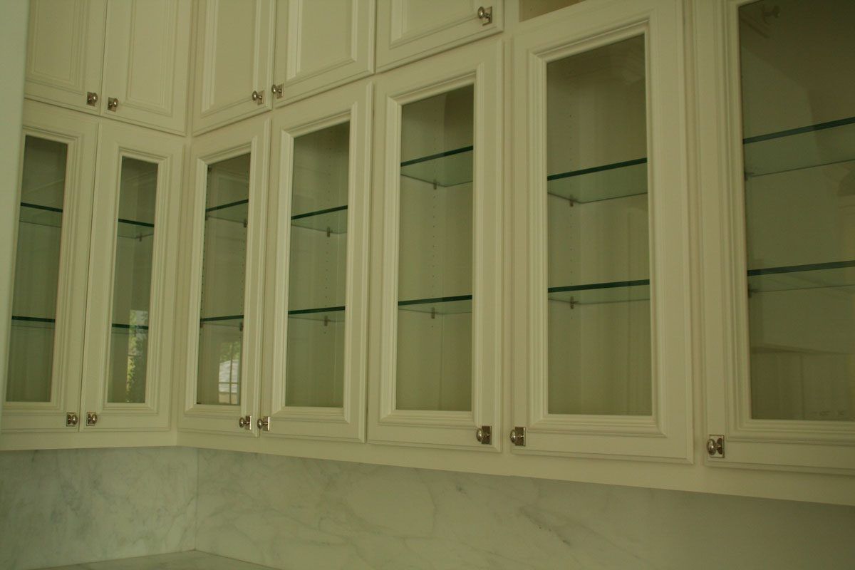 A kitchen with white cabinets and glass doors.