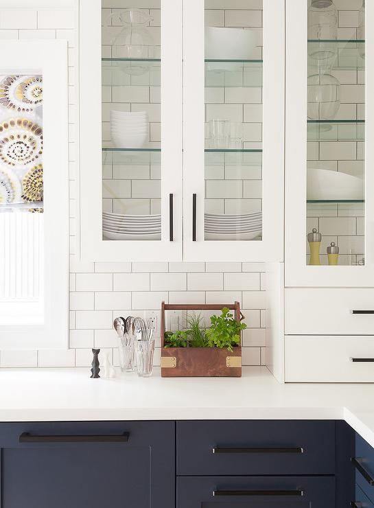 A kitchen with blue cabinets and white cabinets with glass doors