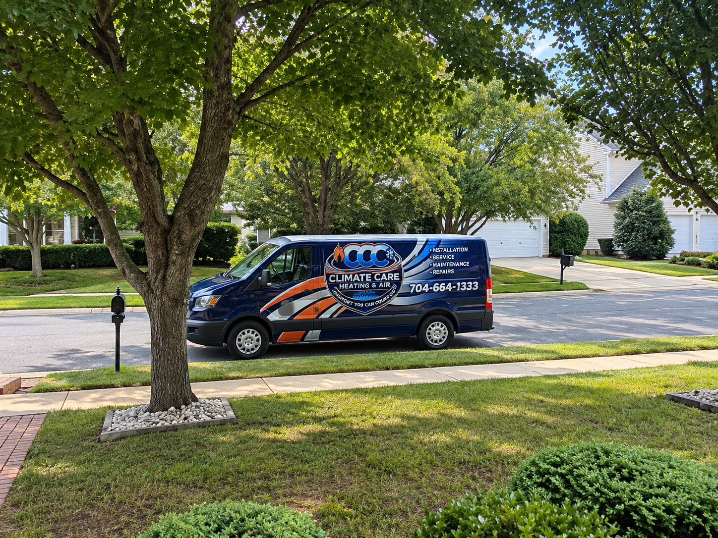 Blue service van with orange graphics parked on a tree-lined residential street.