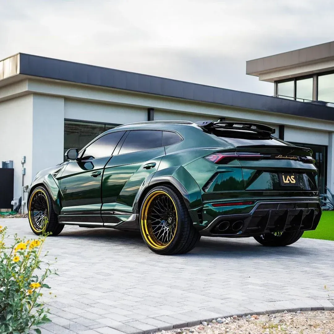 Dark green modified SUV with gold rims parked in a modern driveway