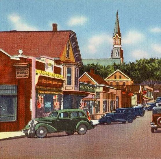 Vintage street scene with cars, shops, and a church steeple in a small town.
