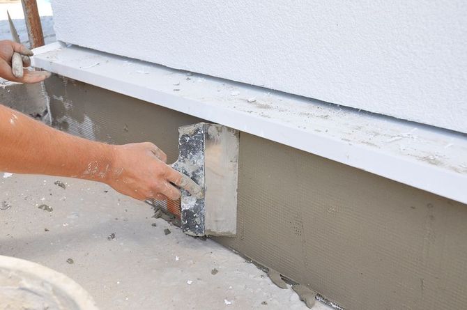 A person is using a spatula to plaster a wall.