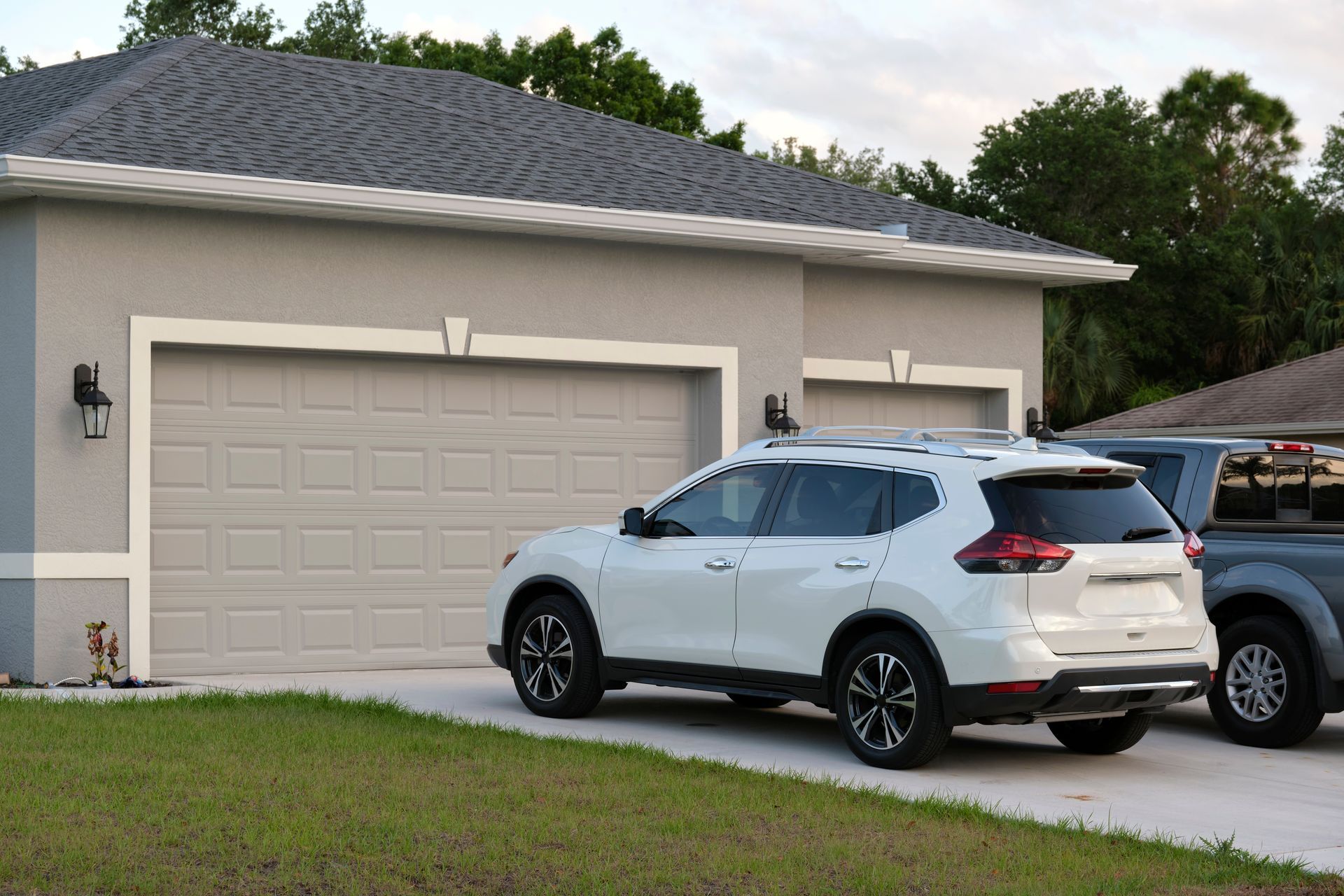White SUV parked in front of a beige suburban house with a two-car garage