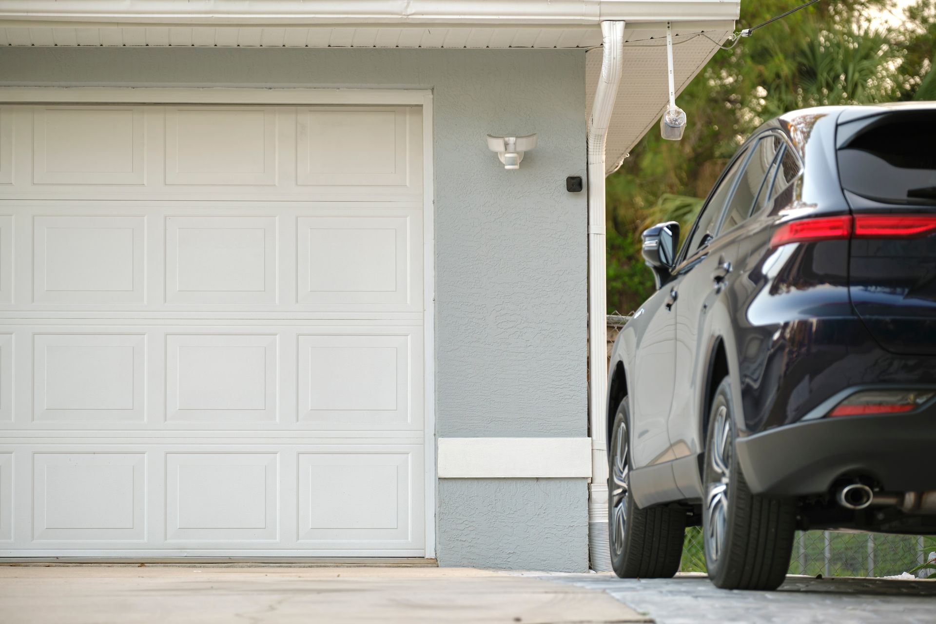 Black SUV parked beside a white garage in a suburban driveway