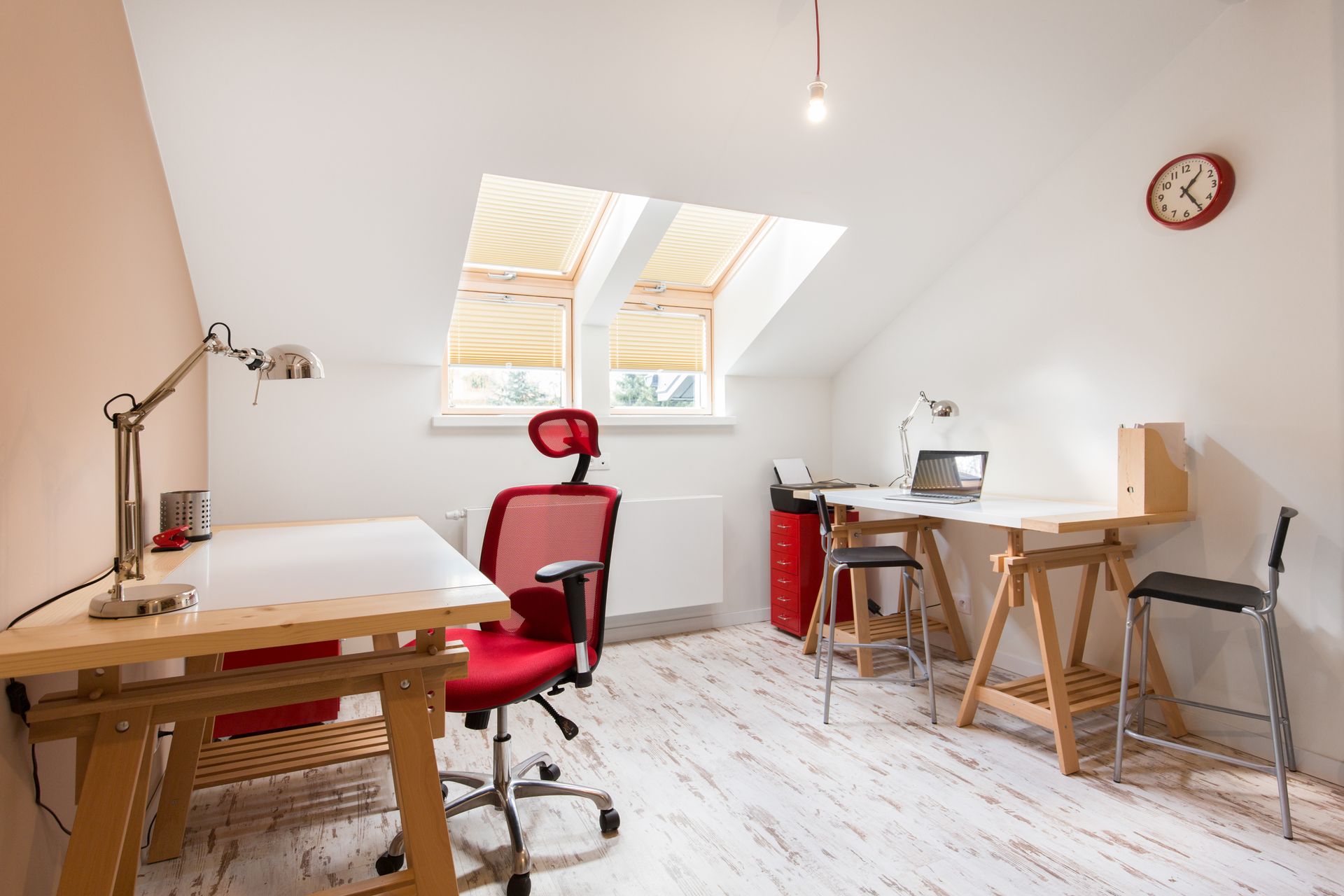 Bright attic home office with desks, red chair, skylight, and computer workstation