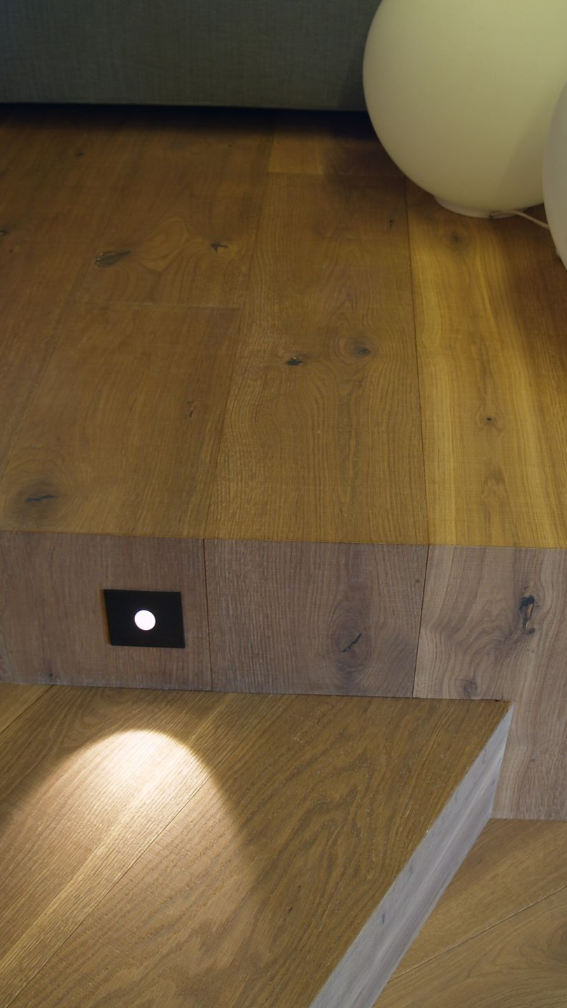 Escalier en bois avec éclairage encastré, mettant en valeur des tons et des textures chauds.