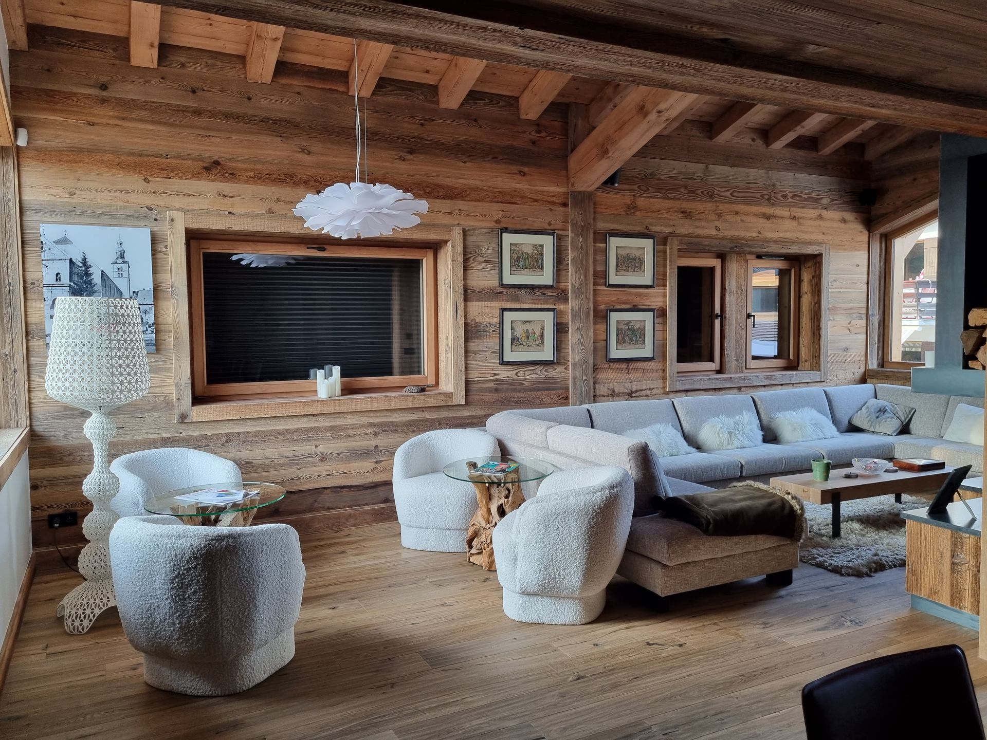 Salon chaleureux avec murs et plafond lambrissés, sièges confortables et une grande fenêtre.