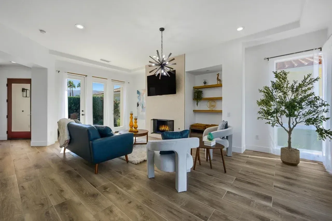Living room with teal sofa, fireplace, and open doors to a patio, neutral tones.