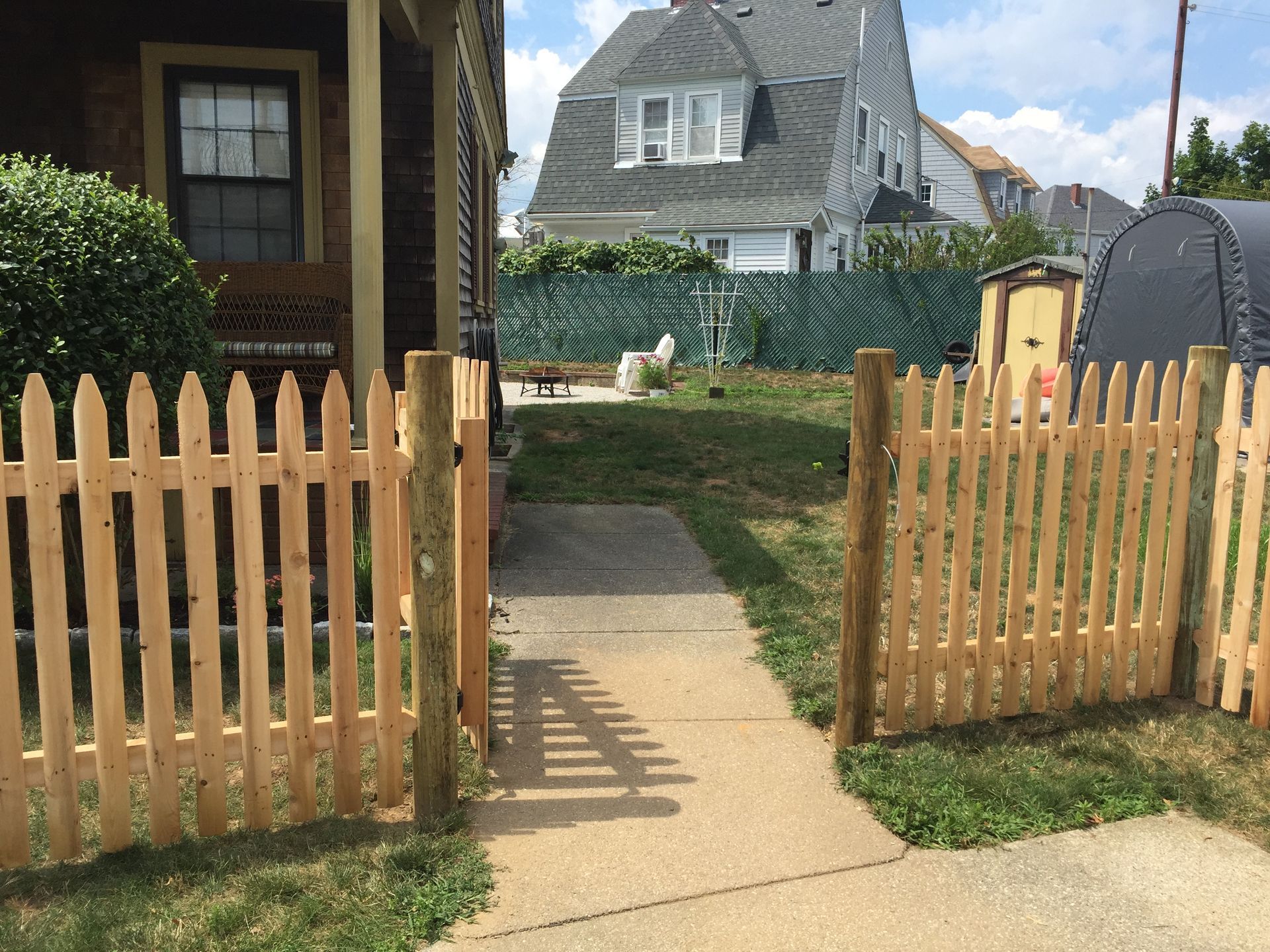 A wooden picket fence is in front of a house.
