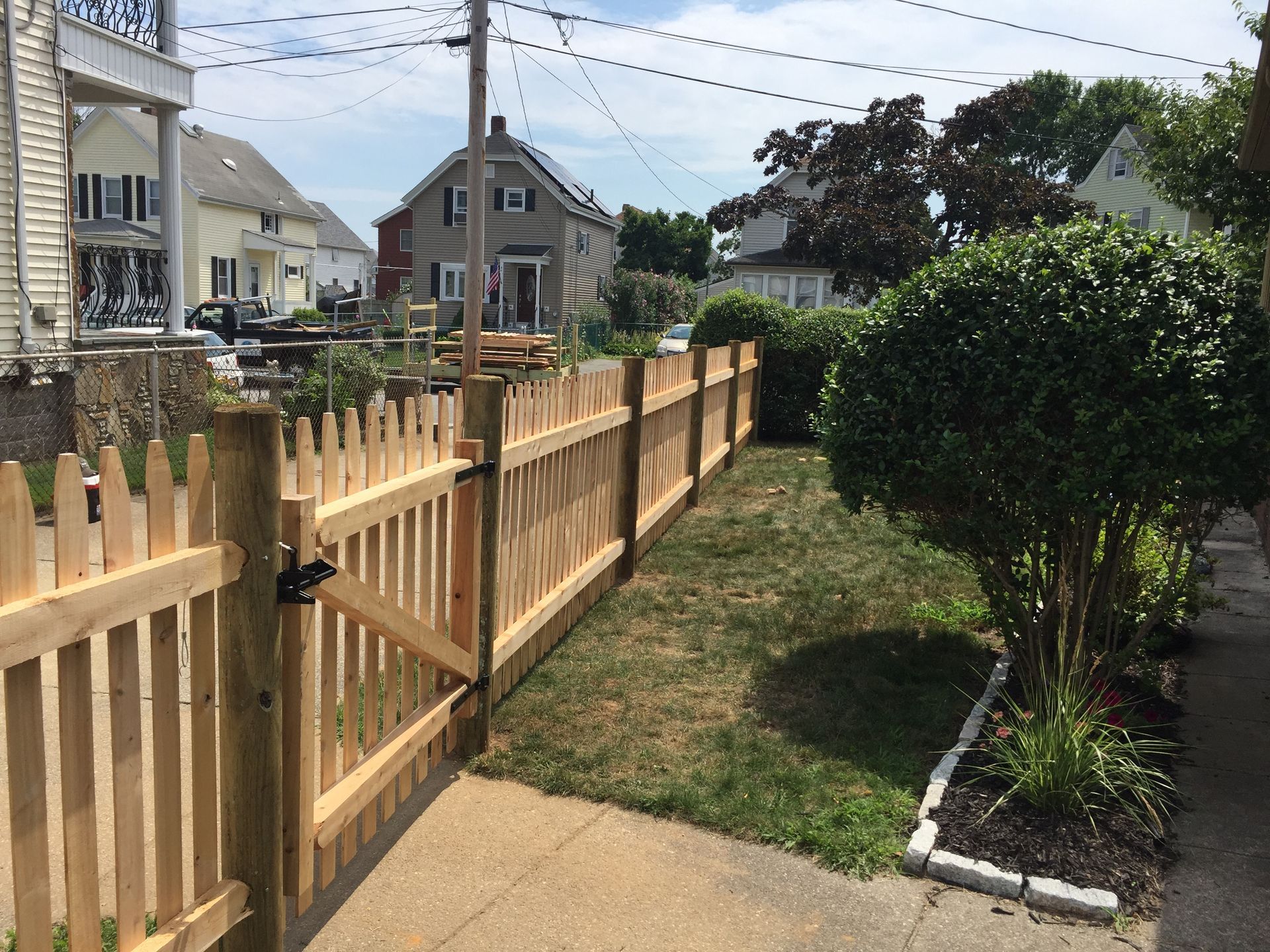 A wooden picket fence surrounds a lush green yard.
