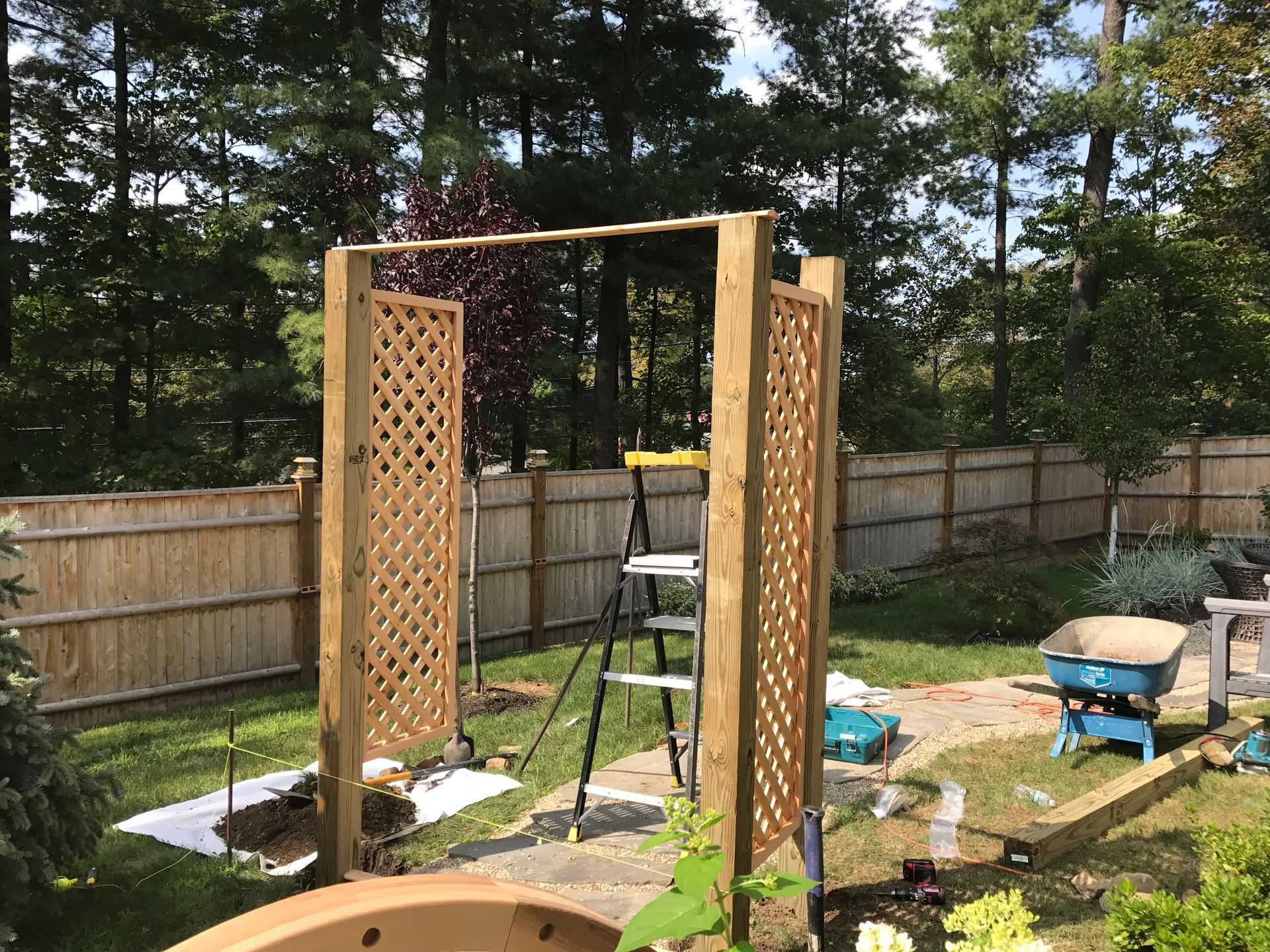 A wooden archway is being built in a backyard.