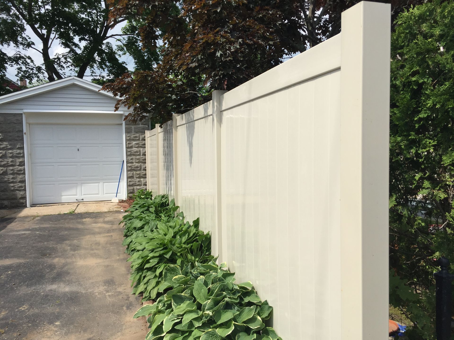A white fence surrounds a house with a white garage door