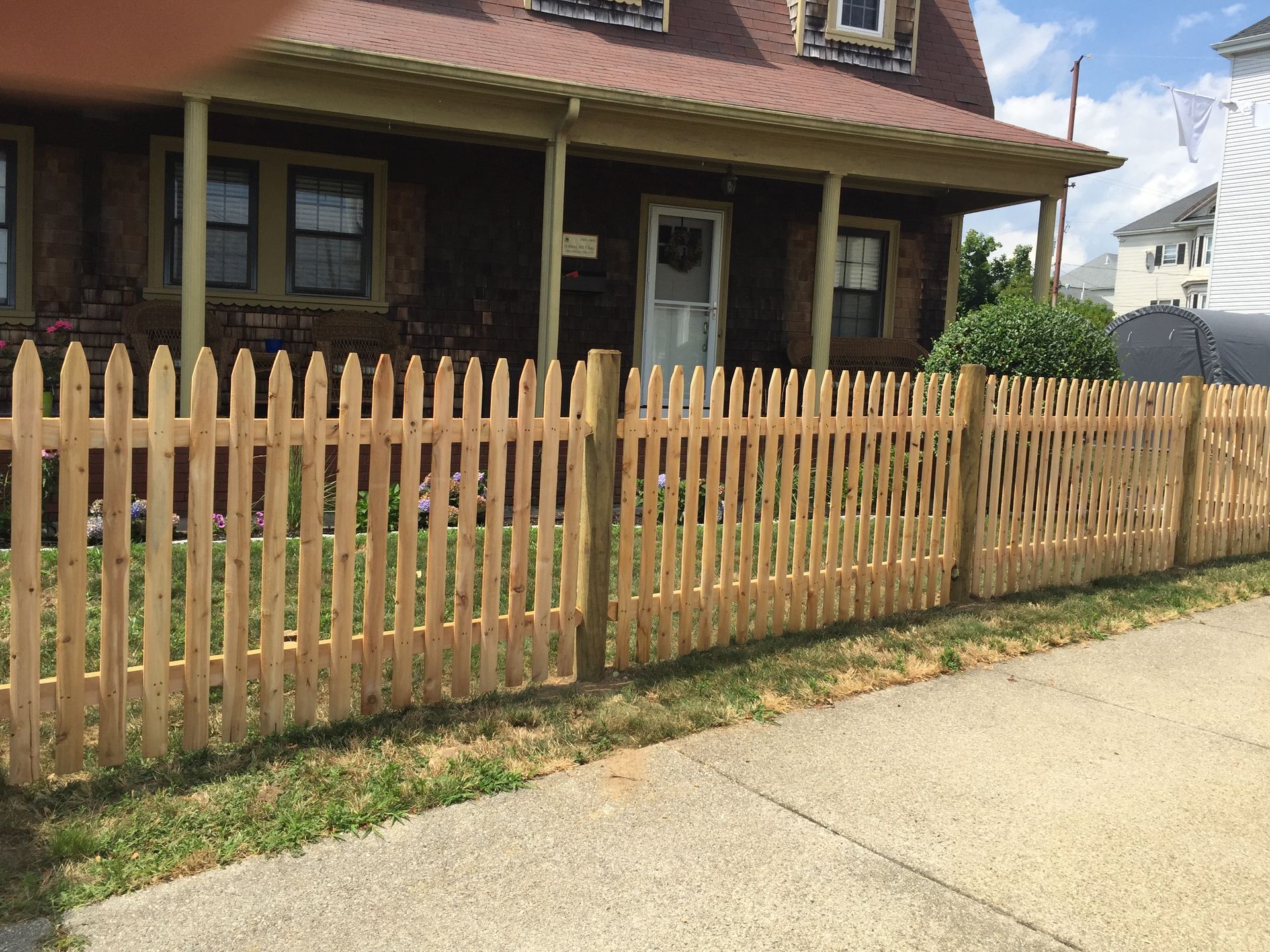 A wooden picket fence is in front of a house.
