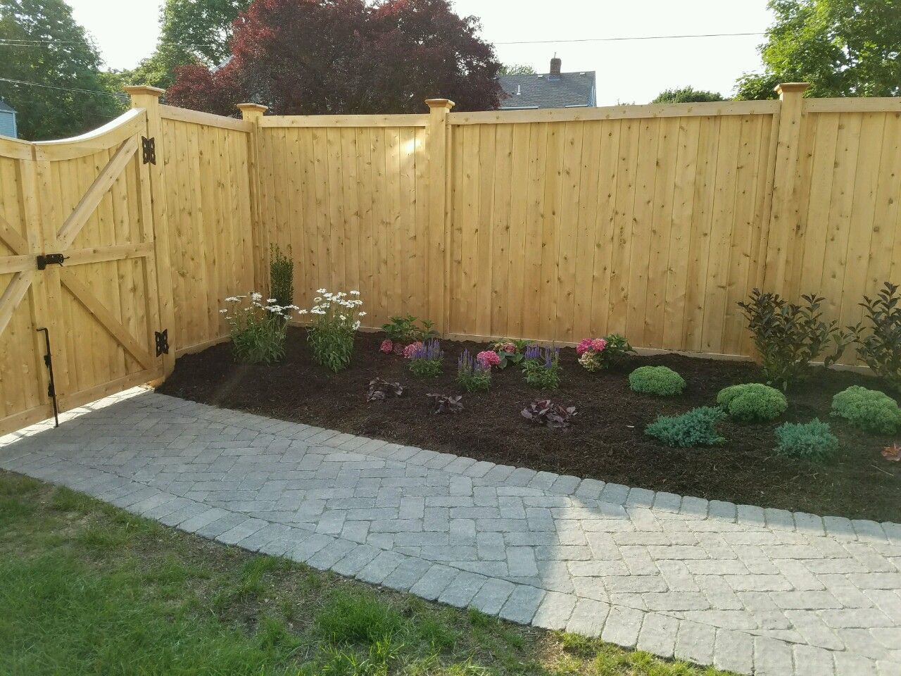 A wooden fence with a brick walkway leading to it