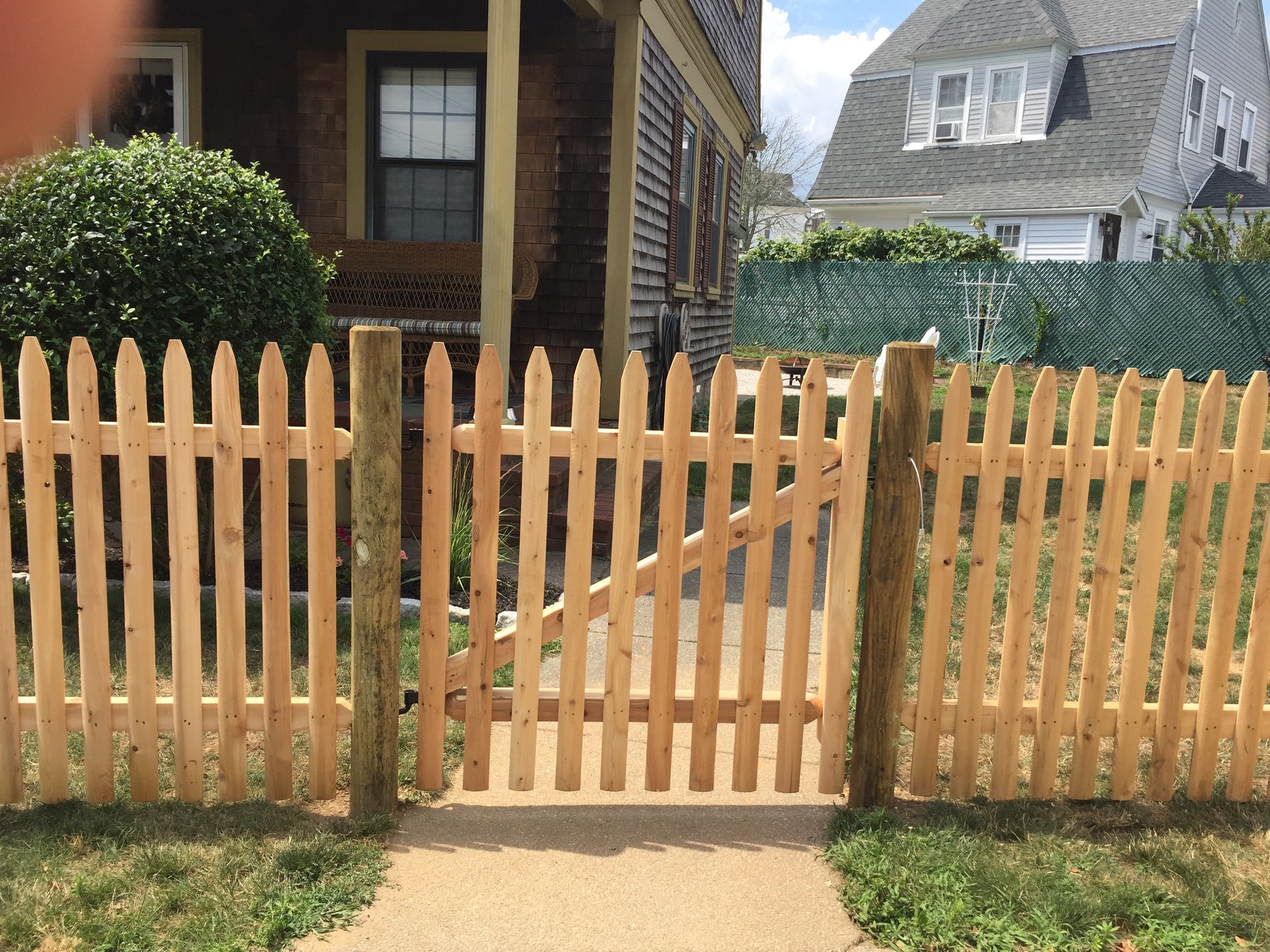 A wooden picket fence with a gate in front of a house.
