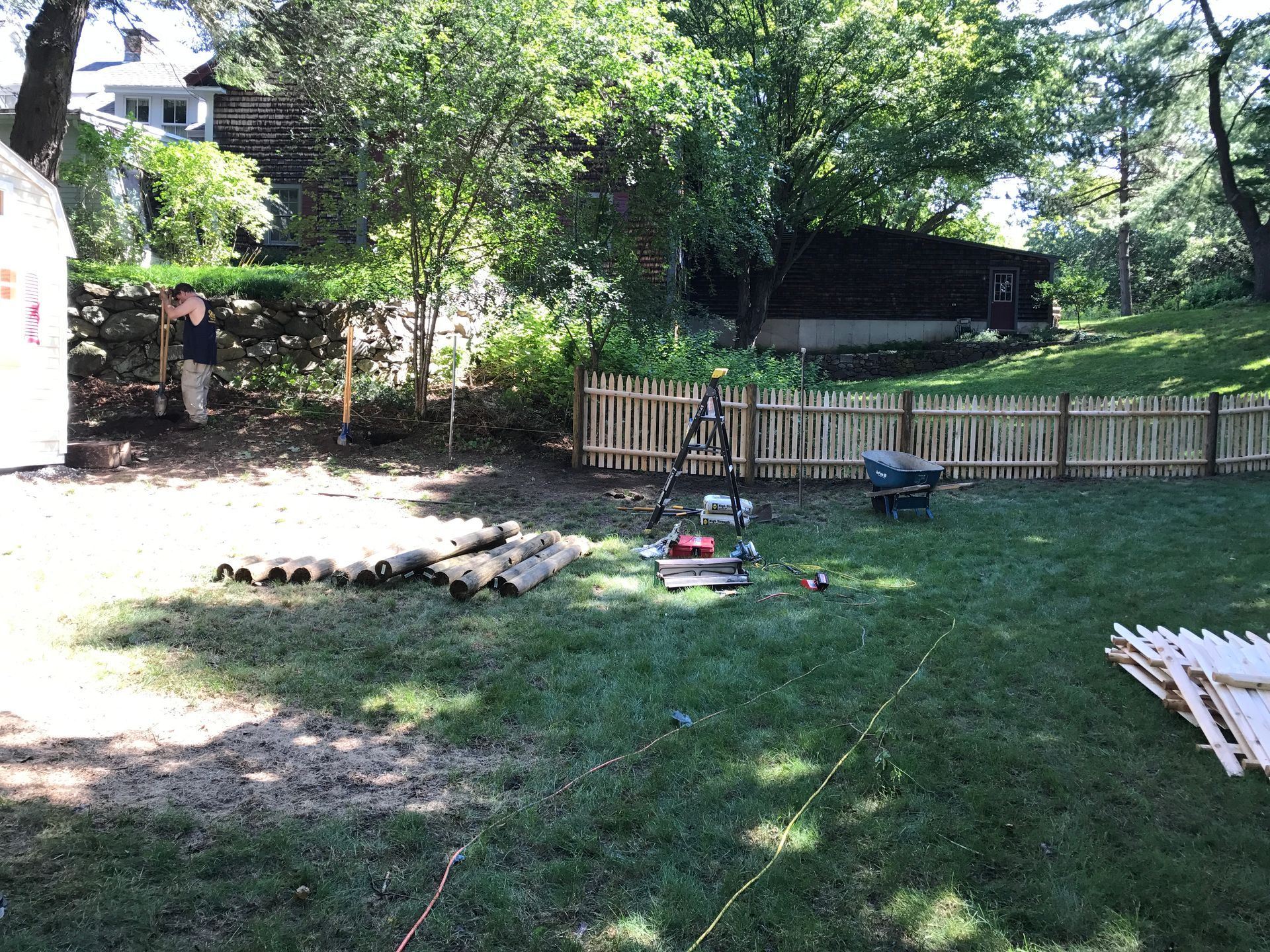 A backyard with a wooden fence , chairs and a lawn mower.