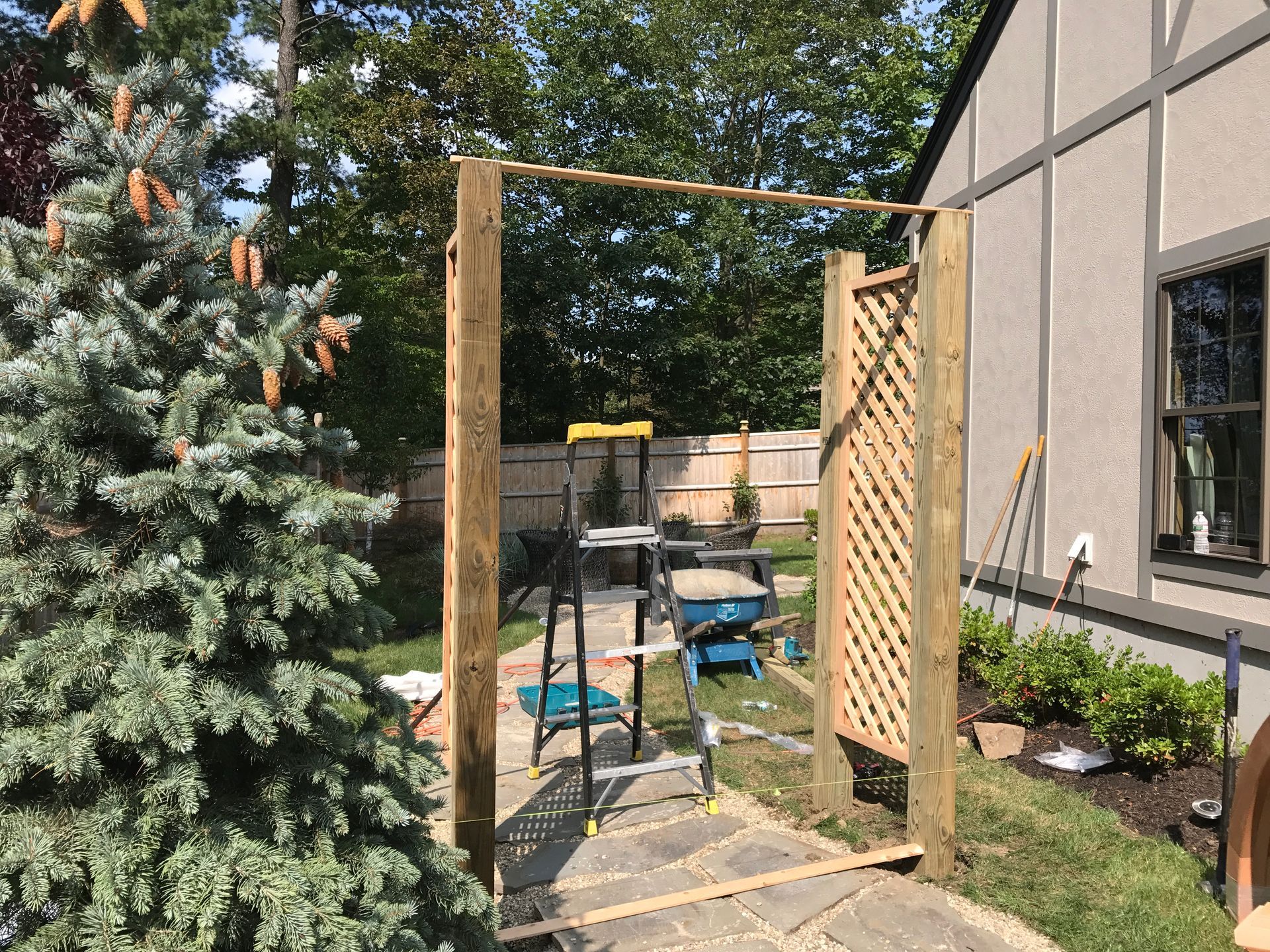 A wooden fence is being built in the backyard of a house.