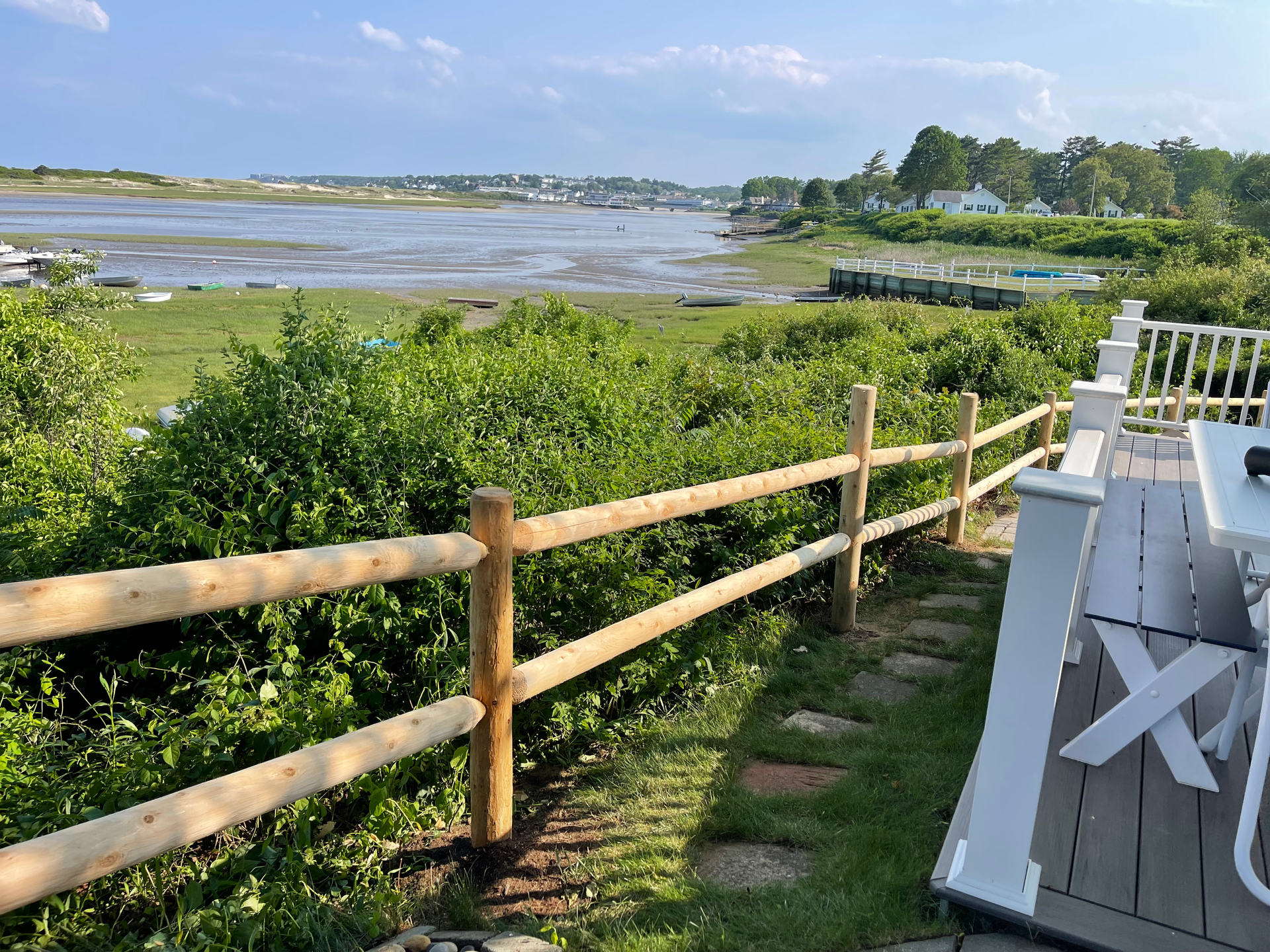 A wooden fence surrounds a deck overlooking a body of water.
