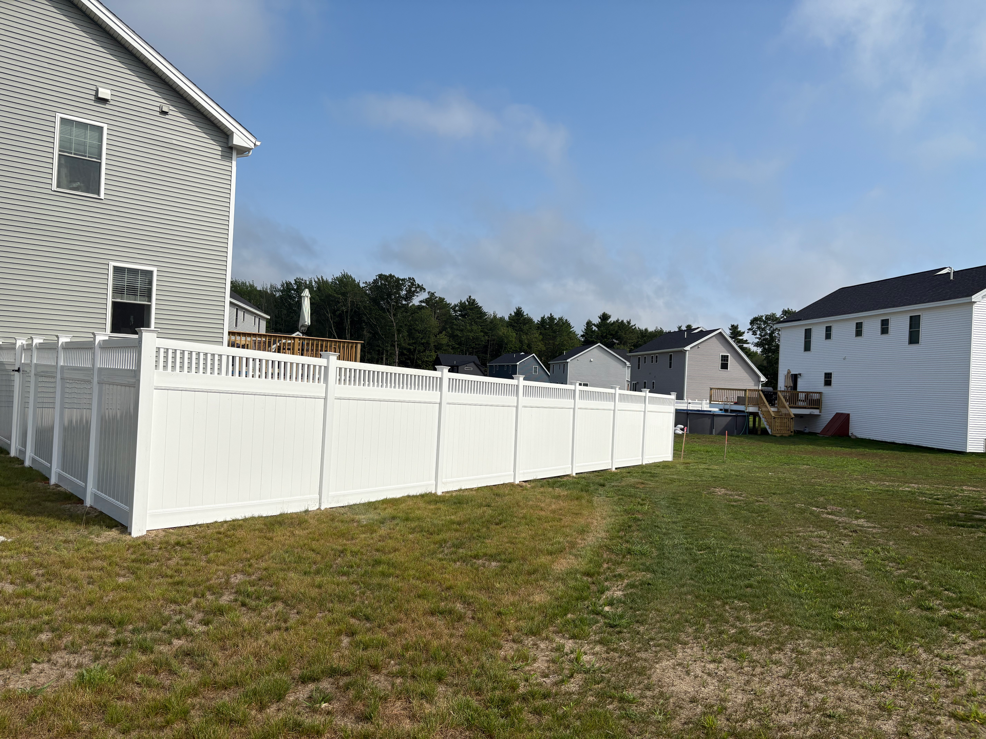 There is a white fence in the backyard of a house.