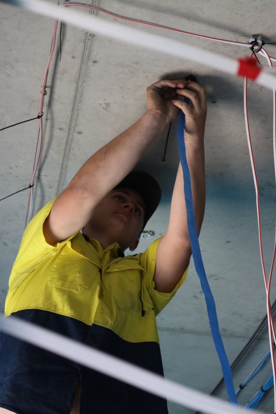 A Man in a Yellow Shirt is Working on a Ceiling — Chill-Rite Refrigeration and Air Conditioning in Dubbo, NSW