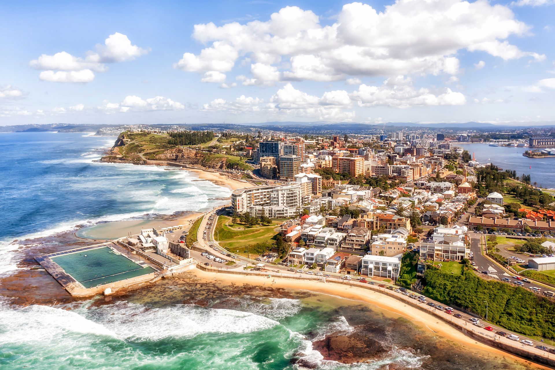 Coastal city aerial view with buildings, beach, ocean, and a swimming pool. Sunny day with blue sky— Chill-Rite Refrigeration and Air Conditioning in Newcastle, NSW