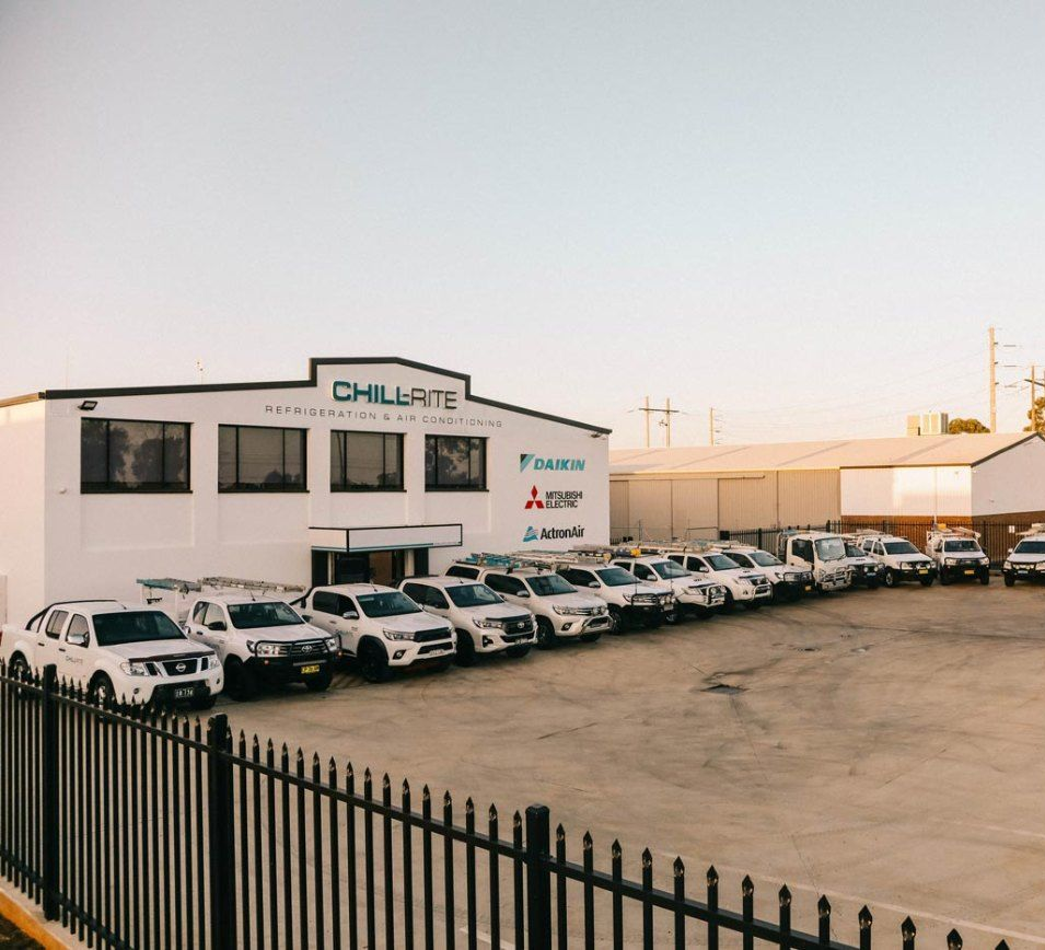 A Row of White Cars Are Parked in Front of a Building — Chill-Rite Refrigeration and Air Conditioning in Dubbo, NSW