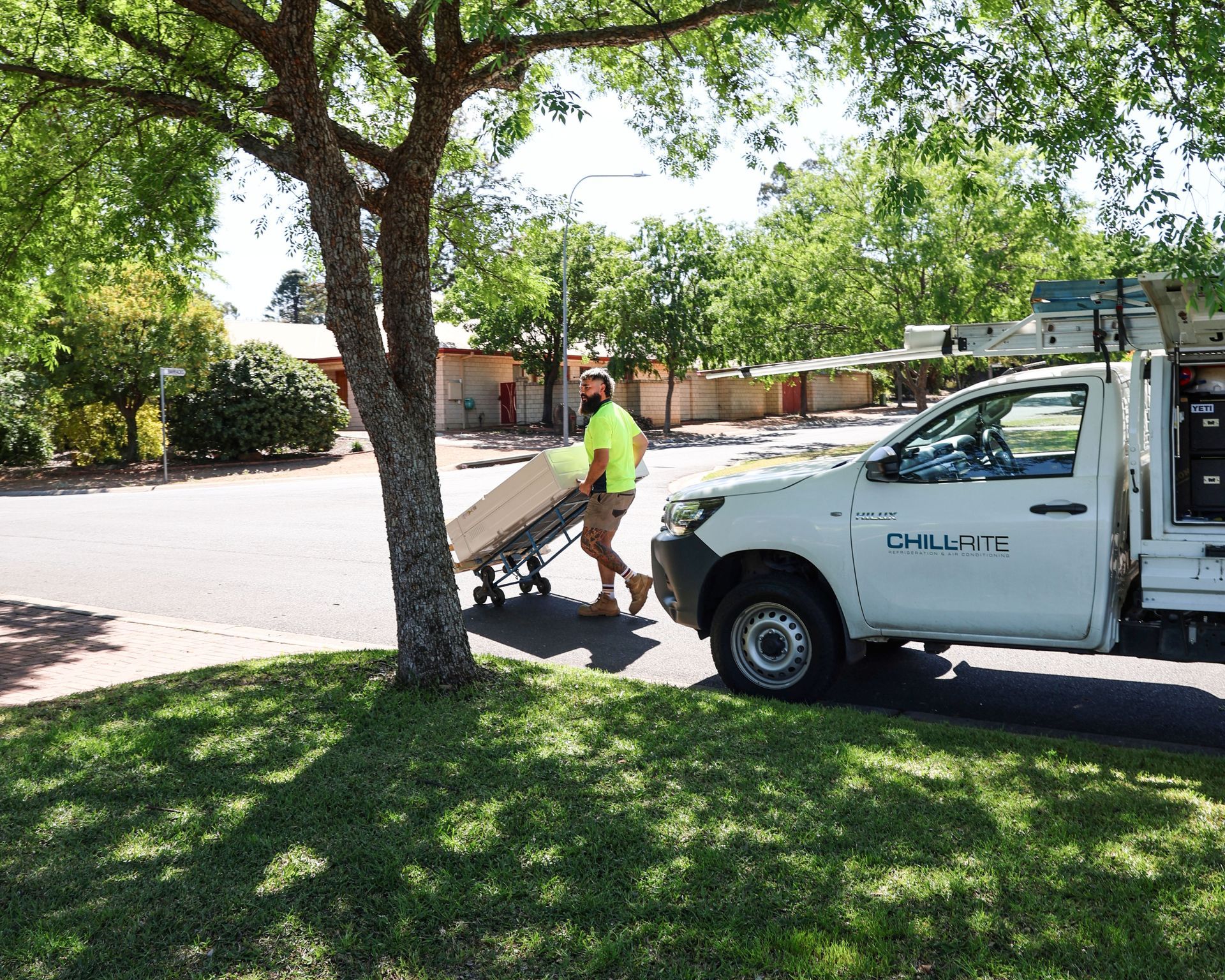 Worker Pushing a Wheelbarrow Past a White Utility Truck — Chill-Rite Refrigeration and Air Conditioning in Wagga Wagga, NSW