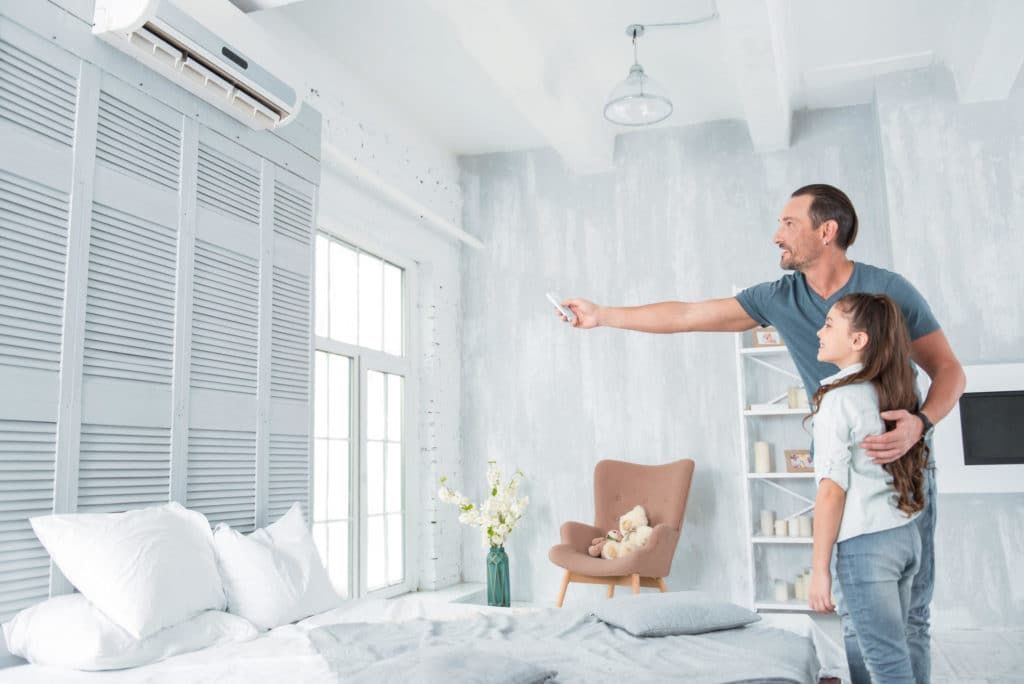 A Man and a Girl Are Standing in a Living Room Looking at an Air Conditioner — Chill-Rite Refrigeration and Air Conditioning in Dubbo, NSW