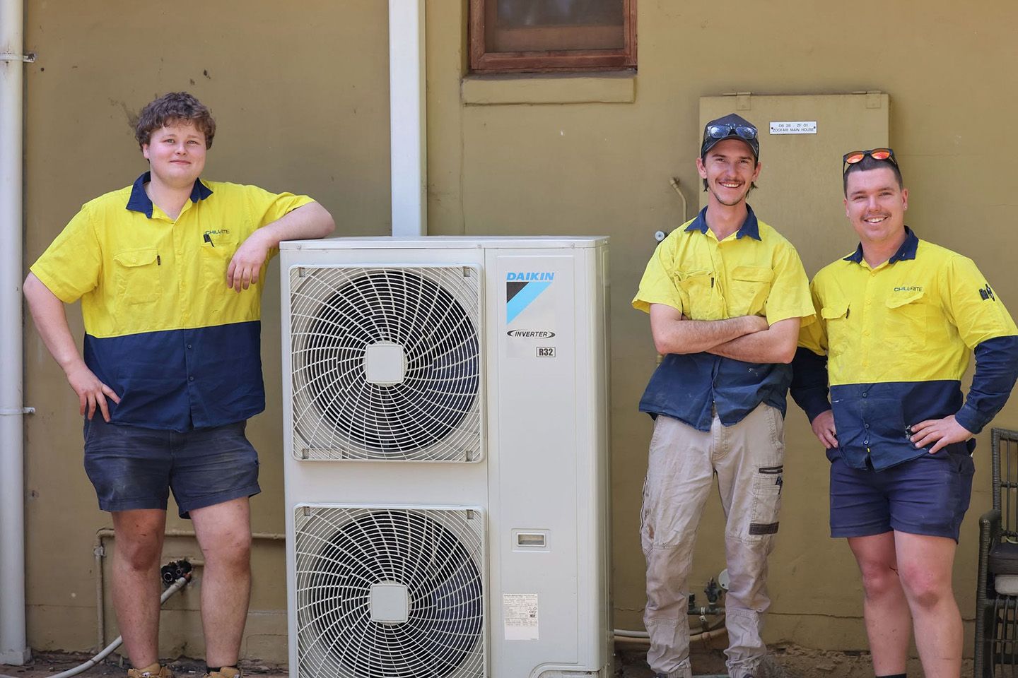 Professional air conditioning installers beside a newly installed outdoor unit