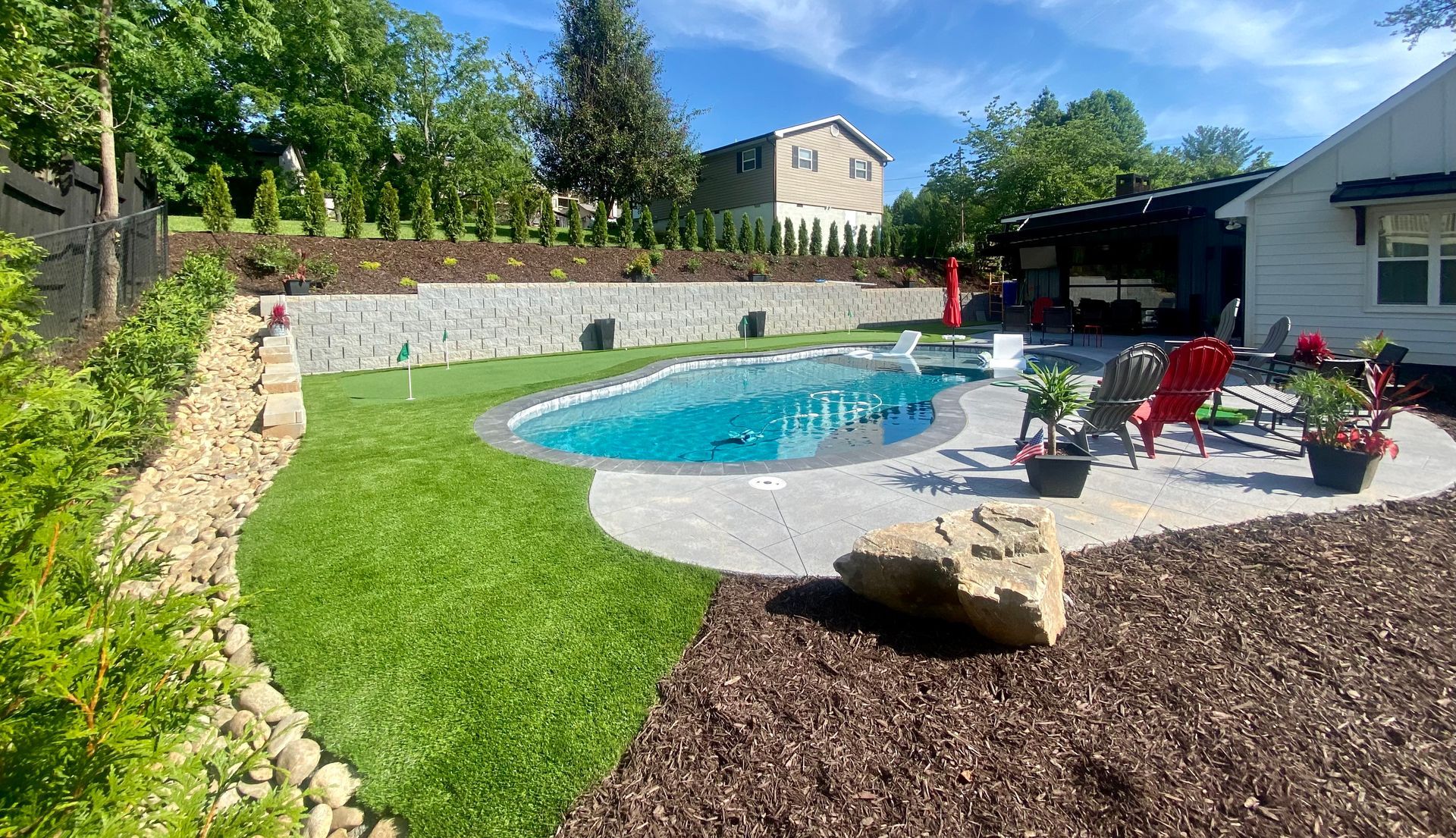 There is a large swimming pool in the backyard of a house.