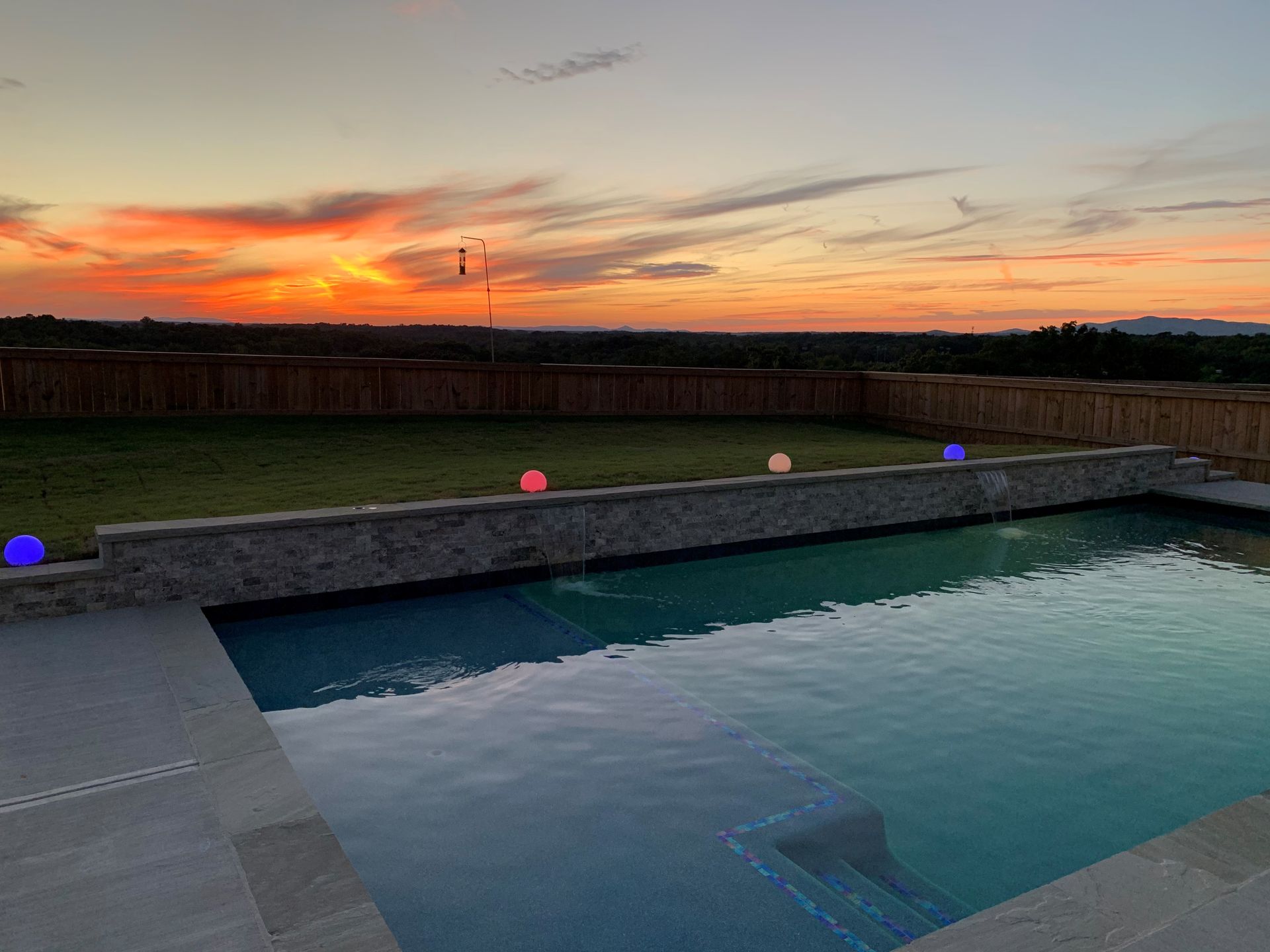 A large swimming pool with a sunset in the background.