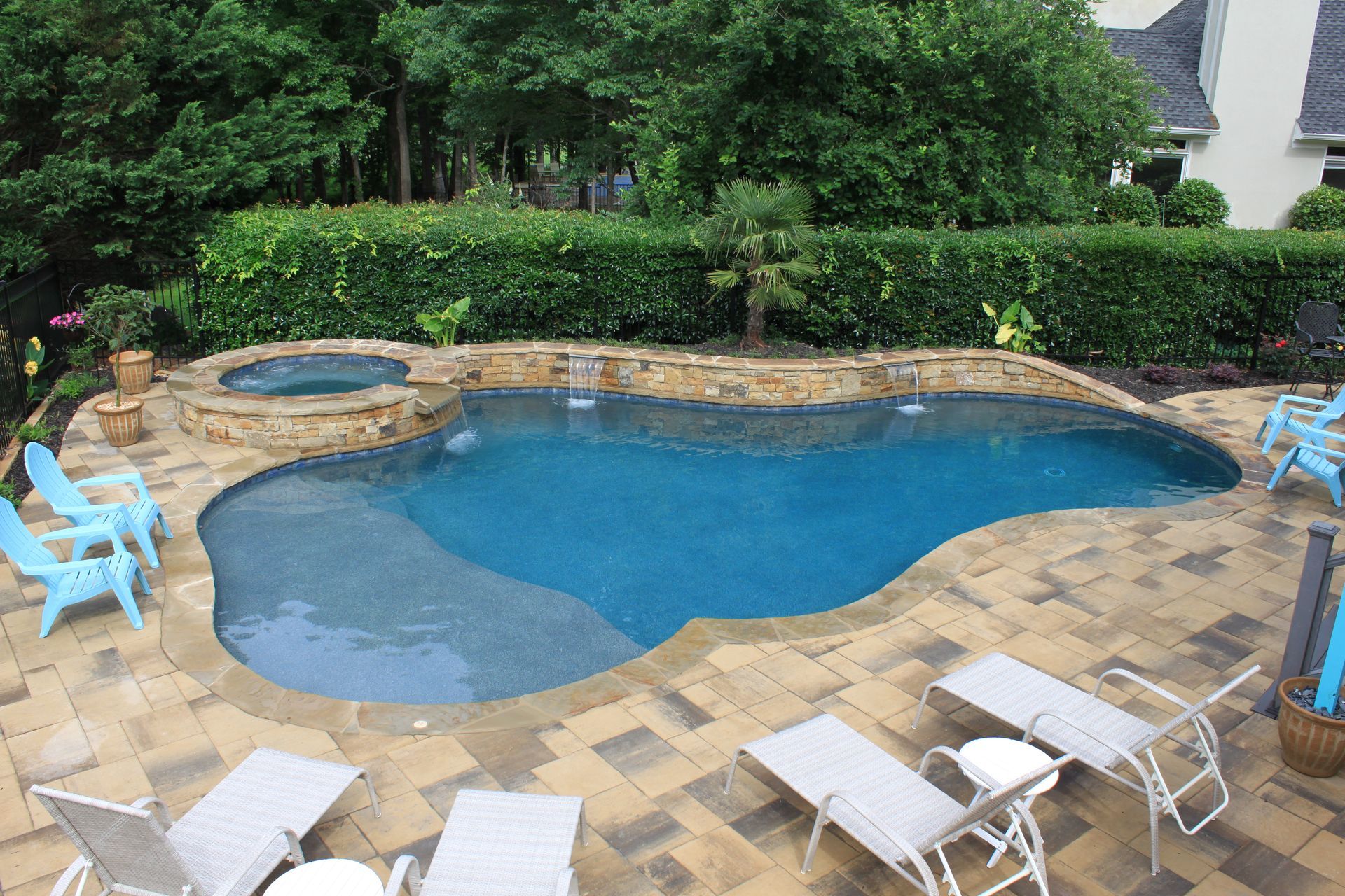A large swimming pool is surrounded by chairs and a patio.